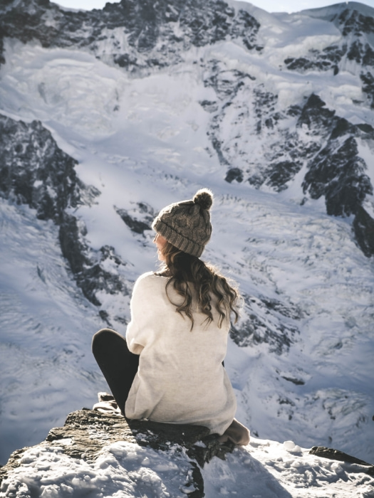 Chica sentada en una paisaje montañosos nevado