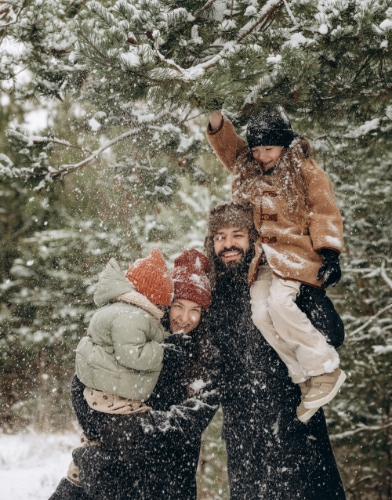 Family playing in the snow in the middle of a forest